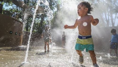 Nicolas Chapman enjoys cooling off at the splash pad at the Atlanta Botanical Garden on Friday. JOHN SPINK / JSPINK@AJC.COM
