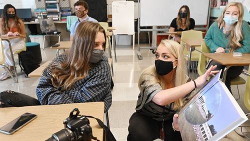 A scene from October 2020 of students wearing masks at Milton High School. Jordan Kohanim talks to one of her students Lara Reinsch, 16, as she works with students to create a yearbook that marks the school's 100th anniversary at Milton High School.  Milton Historical Society is separately making a documentary of the pandemic.  (Hyosub Shin / Hyosub.Shin@ajc.com)