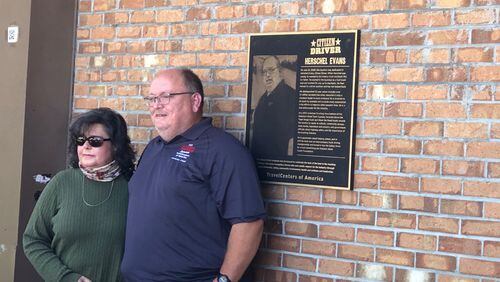 Herschel Evans and his wife, Holly, pose in front of his “Citizen Driver of the Year” plaque outside of the big truck stop on Hollowell Parkway at I-285 on Wednesday, October 14th, 2020. Credit: Doug Turnbull, WSB Traffic