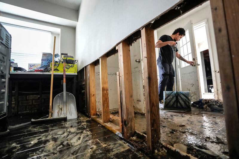Anthony Dusauzay shovels debris in the laundry room of his flood-damaged home as he works to clean it up in the River Plantation neighborhood on Monday, May 6, 2024, in Conroe, Texas. (Brett Coomer/Houston Chronicle via AP)