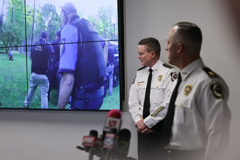 (Left to right) Cobb County Police Chief Stuart VanHoozer and Captain Darin Hull watch video of the arrest of the Midtown shooter during a news conference at Cobb County Police Headquarters on Tuesday. (Natrice Miller/natrice.miller@ajc.com)