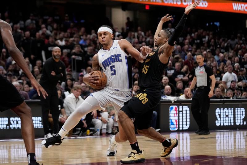 Orlando Magic forward Paolo Banchero (5) drives around Cleveland Cavaliers forward Isaac Okoro, right, in the second half of Game 7 of an NBA basketball first-round playoff series, Sunday, May 5, 2024, in Cleveland. (AP Photo/Sue Ogrocki)