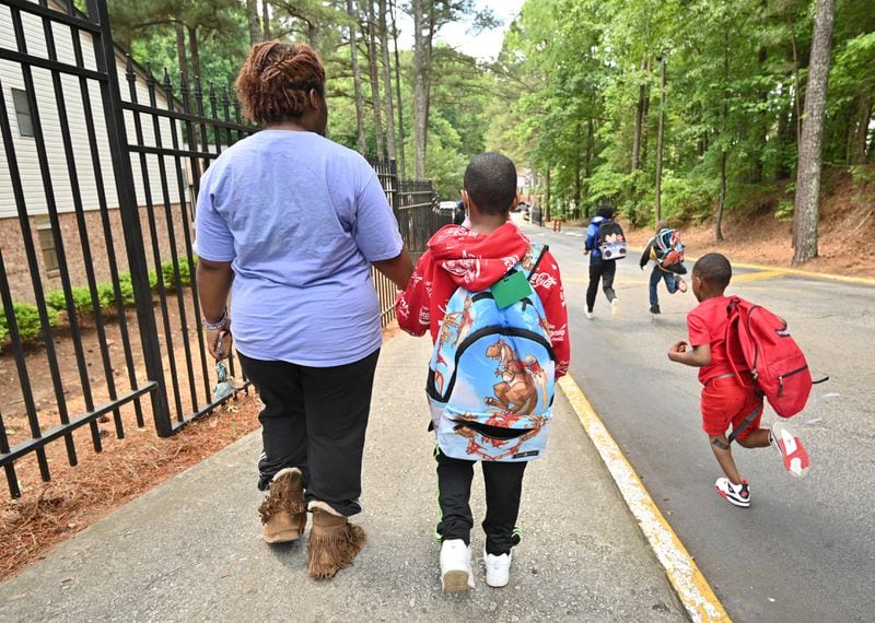 May 12, 2022 Atlanta - Alexis Cargile and her son Logan, 7, hold hands as they walk to their apartment home after getting off from a school bus outside The Hills at Greenbriar Apartments in Southwest Atlanta on Thursday, May 12, 2022. (Hyosub Shin / Hyosub.Shin@ajc.com)