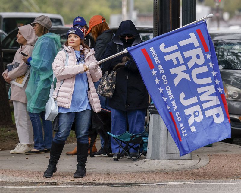 A woman waves a Donald Trump and John F. Kennedy Jr. flag along Elm Street at Dealey Plaza Tuesday in downtown Dallas. The group believes John F. Kennedy Jr., who died in plane crash in 1999, will return and reinstate Donald Trump as president. 