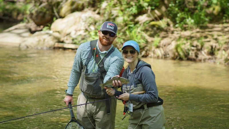 Guide Jake Darling, an angler from Winged Reel and Heather Mulling celebrate a catch at the Casting for Recovery recent retreat in the north Georgia mountains. 
Courtesy of Casting for Recovery / Justin Dobson.