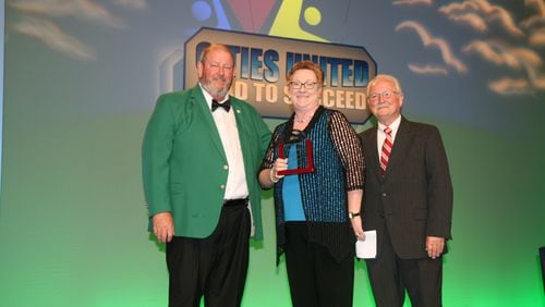 Georgia Municipal Association President and Dublin Mayor Phil Best (left) and Perry Mayor Pro Tem Randall Walker (right) present former Decatur City Manager Peggy Merriss with a Municipal Government Hall of Fame plaque.Courtesy Georgia Municipal Association