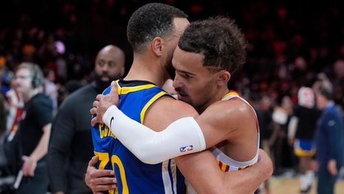 Atlanta Hawks guard Trae Young (11) and Golden State Warriors guard Stephen Curry (30) embrace after an NBA basketball game Saturday, Feb. 3, 2024, in Atlanta. (AP Photo/John Bazemore)
