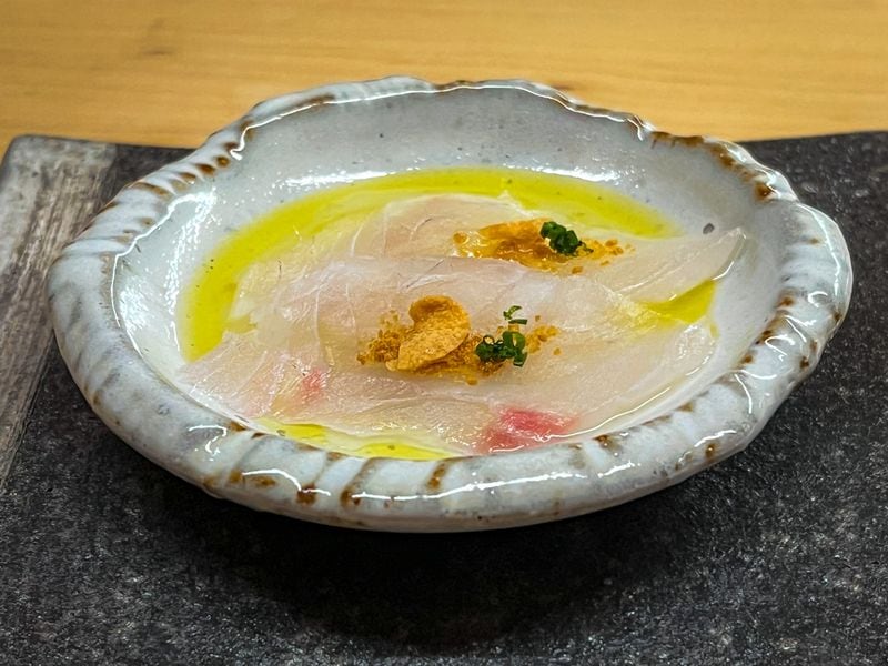Each meal at Omakase by Yun starts with a fish carpaccio, such as this tai snapper with miso and garlic. Henri Hollis/henri.hollis@ajc.com