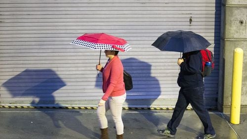 Pedestrians use their umbrellas to shield themselves from a light rain shower.