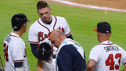 Atlanta Braves first baseman Freddie Freeman leaves the field with a trainer as manager Brian Snitker looks on after being hit by a pitch from Phillies Hoby Milner during the eight inning Wednesday, April 18, 2018, in Atlanta.