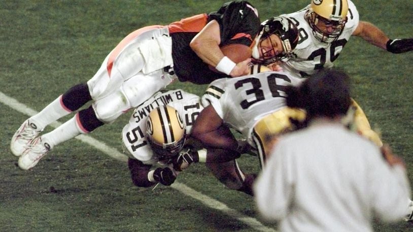 In this Jan. 25, 1998, file photo, Denver Broncos quarterback John Elway is flipped by Green Bay Packers' Brian Williams (51) and Elroy Butler (36) while running for a first down during Super Bowl XXXII at Qualcomm Stadium in San Diego. (AP Photo/Elaine Thompson, File)