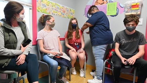 Margarett Bell, 14, receives a first dose of the Pfizer-BioNTech vaccine from Melissa Dalton, RMA, as her mother Jessica Bell (left), sister Mary Frances Bell, 12, and brother Griffin Bell (right), 17, look at Dekalb Pediatric Center on May 12, 2021.