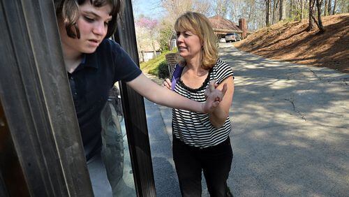 Patti Grayson helps her daughter Caroline, 12, who has autism, getting off from a school bus near their home in Sandy Springs on Tuesday, April 1, 2014. Some of Georgia’s most severely disabled students are bussed long distances to go to schools outside their communities that offer specialized programs supporting their needs. Students with disabilities and their parents often feel disconnected to their communities when they have to travel great distances to attend school. In Fulton County, students with disabilities often must ride a bus more than an hour to attend specialized programs at schools. HYOSUB SHIN / HSHIN@AJC.COM