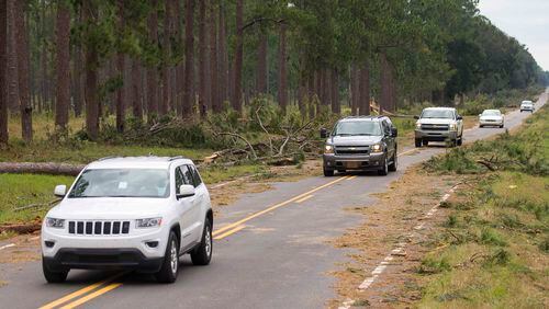 Cars cautiously pass downed pine trees as they travel along State Road 91 in Newton last Thursday. The Georgia Department of Transportation says nearly all state highways have reopened after Hurricane Michael. (ALYSSA POINTER/ALYSSA.POINTER@AJC.COM)