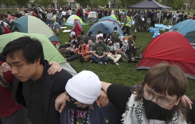 Pro-Palestinian protesters link arms around campers as police show up to their encampment on Washington University's campus, Saturday, April 27, 2024, in St. Louis, Mo. Dozens were arrested during the protest. (Christine Tannous/St. Louis Post-Dispatch via AP)