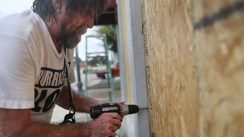 FILE PHOTO: Al Smith puts plywood over a window as he prepares a building for the arrival of hurricane Michael on October 9, 2018, in Port St. Joe, Florida.