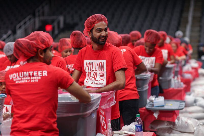 Arish Valliani (center) has a laugh while helping others pack 1 million meals at the event at State Farm Arena on Saturday, Oct. 5, 2019, in Atlanta. BRANDEN CAMP/SPECIAL TO THE AJC