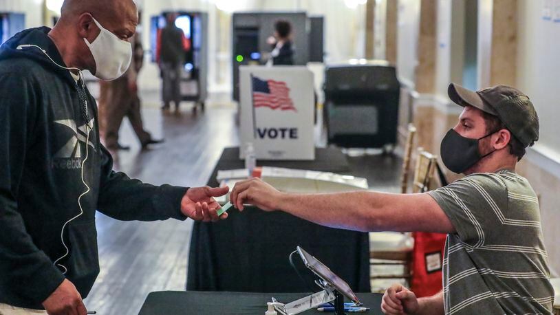 C.J. Andrews (right) checks in voters at Park Tavern located at 500 10th St. NE in Atlanta on Tuesday, Nov. 2, 2021. (John Spink / John.Spink@ajc.com)