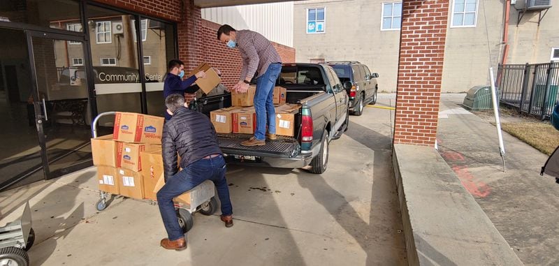 Four elementary schools in Lawrenceville were excited to receive books for their students from the First Book Club 165 of Lawrenceville First Baptist Church. Pictured are: Senior Pastor Inman Houston, standing in the truck, receiving a box from Logan Ferrell, student ministry director. Associate Pastor Radu Calibu is in front. (Courtesy of Vicki Aiken)