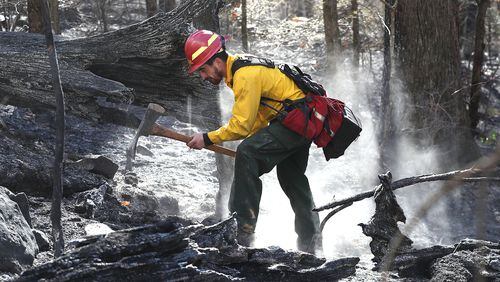 Firefighter Cody Henderson of New Mexico works on structure protection, putting out a hot spot above a home on the Tallulah River Road near the Georgia and North Carolina border while fighting the Rock Mountain Fire on Monday, Nov. 21, 2016, in Clayton.