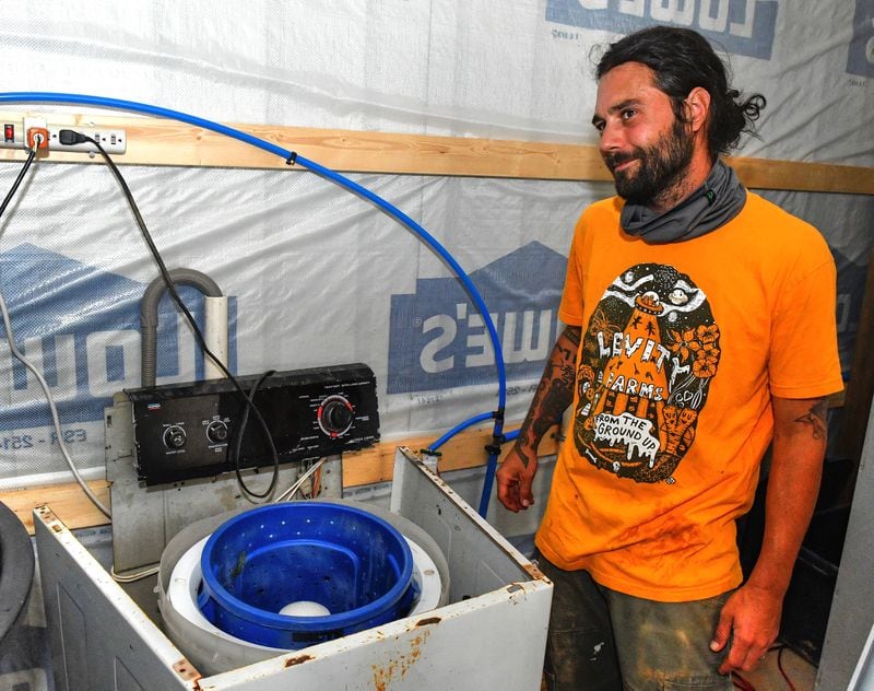 Owner Zach Richards shows his homemade dryer (think industrial-sized salad spinner) made from a washing machine internals and spindle that uses the high-speed spin cycle to spin dry lettuces and other leafy vegetables at Levity Farms in Madison. (Chris Hunt for The Atlanta Journal-Constitution)