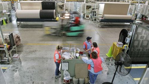 A forklift speeds by machines and workers on the production floor of a Mohawk Industries rug manufacturing plant in Calhoun, Ga., in 2006. Recently, the company has faced allegations that it inflated financial results, misleading investors. (AP Photo/Ric Feld)