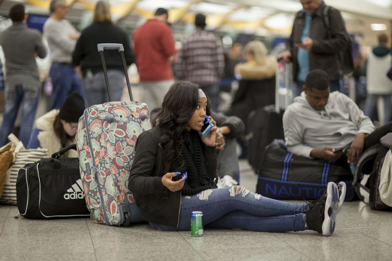 A Delta passenger sits on the floor while waiting in line at Hartsfield-Jackson International Airport after Delta Air Lines grounded all domestic flights due to automation issues, Sunday, Jan. 29, 2017, in Atlanta. (AP Photo/Branden Camp)