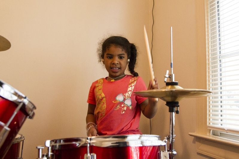 Aniyah Royal, 7, a student in Atlanta, plays the drums during an afternoon session of the Kevin Baker Music Program. REANN HUBER / REANN.HUBER@AJC.COM