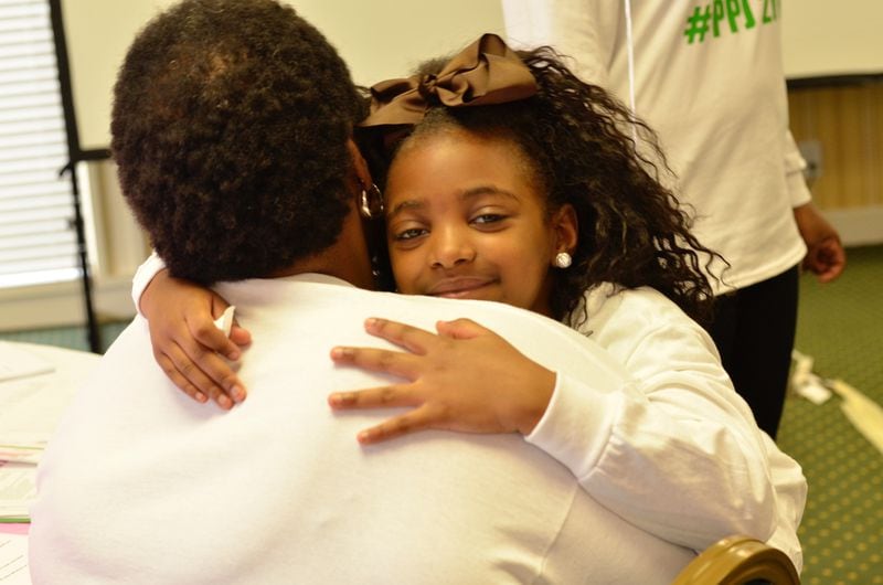 I Am B.E.A.U.T.I.F.U.L. co-founder Zenobia Edwards gets a hug from one of the girls in the non-profit's Beginnings program. The  L  in B.E.A.U.T.I.F.U.L. stands for LOVED. CONTRIBUTED