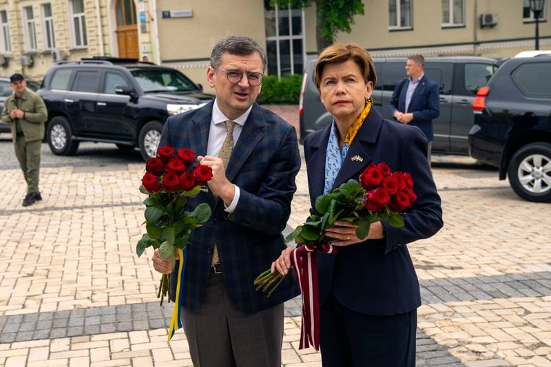 Ukraine Foreign Minister Dmytro Kuleba, left, speaks to his Latvia counterpart Baiba Braze before placing flowers at a memorial wall of Ukrainian soldiers killed during the war, at Saint Michael cathedral in Kyiv, Ukraine, Friday, April 26, 2024. Braze visited Kyiv on her first foreign trip to discuss aid for Ukraine, including a plan to build drones. (AP Photo/Francisco Seco)