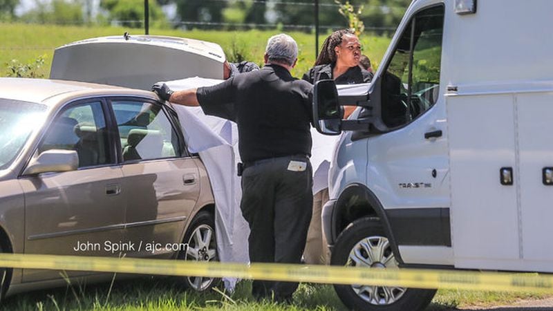 Barrow County Sheriff investigators at Whitley Road and Kilcrease Drive examine a car where a body was found in the trunk.