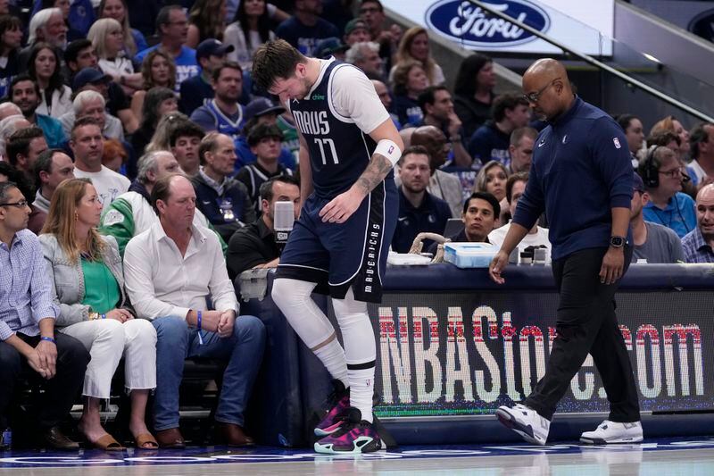 Dallas Mavericks' Luka Doncic slowly walks off the court with a staff member during the first half of Game 2 of the team's NBA basketball first-round playoff series against the Los Angeles Clippers in Dallas, Friday, April 26, 2024. Doncic continued playing in the half. (AP Photo/Tony Gutierrez)