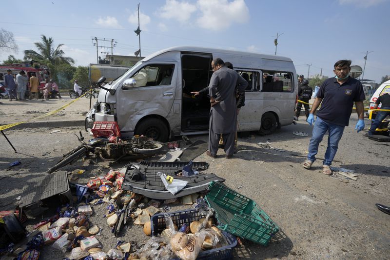Pakistani investigators examine a damaged van at the site of a suicide attack in Karachi, Pakistan, Friday, April 20, 2024. Five Japanese nationals traveling in a van narrowly escaped a suicide attack when a suicide bomber detonated his explosive-laden vest near their vehicle in Pakistan's port city of Karachi on Friday, wounding three passers-by, police said. (AP Photo/Fareed Khan)