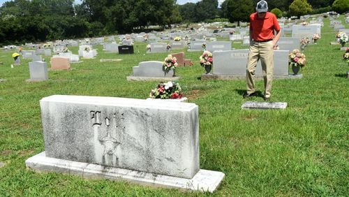 Frank Lott Jr. stands by Polk County Sheriff Frank Lott’s gravestone in Cedartown, Ga. on August 18, 2017. Forty-five years after Polk County Sheriff Frank Lott was shot and killed as he investigated a reported burglary at the local high school, no one has been convicted. There was a suspect who went to trial but a jury acquitted him. Some say Lott’s successor, damaged the case by refusing to share information with other agencies investigating the shooting and by questioning but then releasing the only man to later be charged with the sheriff’s murder. (Rebecca Breyer)