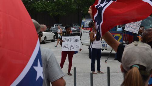 A counter-protestor peacefully holds up a sign before a verbal dispute broke out on the other side of the Yellow Daisy parking lot at Stone Mountain on Saturday, August 1, 2015. DANIEL FUNKE / DANIEL.FUNKE@COXINC.COM