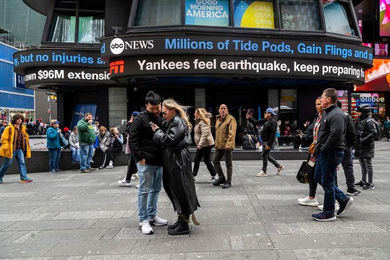 People walk around Times Square as news tickers display news about the earthquake on Friday April 5, 2024 in New York. An earthquake centered between New York and Philadelphia shook skyscrapers and suburbs across the northeastern U.S. for several seconds Friday morning, causing no major damage but startling millions of people in an area unaccustomed to such tremors. (AP Photo/Brittainy Newman)