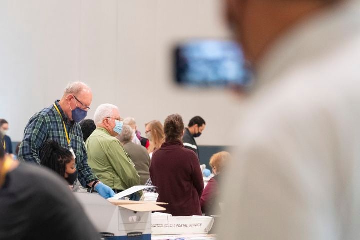 Election workers mill as an observer records with his phone during a Cobb County hand recount of Presidential votes on Sunday, Nov.15, 2020, at the Miller Park Event Center in Marietta. (JOHN AMIS FOR THE ATLANTA JOURNAL-CONSTITUTION)
