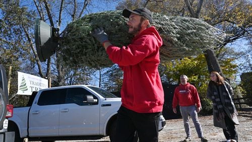 Preparing for the holidays also includes thinking about staying healthy, in addition to trimming the tree. Danny Gorbachov with Tradition Trees helps customers with loading their Christmas tree. (Hyosub Shin / Hyosub.Shin@ajc.com)