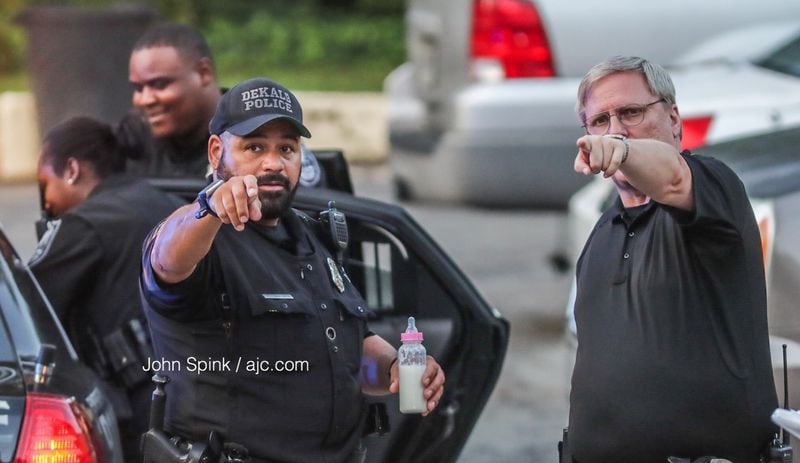 DeKalb police officers prepare a bottle for a baby after the child's mother and older brother were shot multiple times inside their Citrus Court home Monday morning. Both were seriously injured, according to police. JOHN SPINK / JSPINK@AJC.COM.