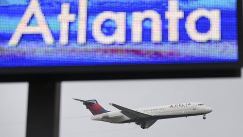 A Delta jet lands, while an electronic board at Hartsfield-Jackson welcomes visitors to Atlanta. JOHN SPINK / JSPINK@AJC.COM