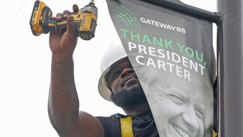 Kyle Williams, a sign installer for Alpha Graphics puts up a banner on Jimmy Carter Boulevard in Norcross on Monday, May 22, 2023. (Natrice Miller/ natrice.miller@ajc.com)