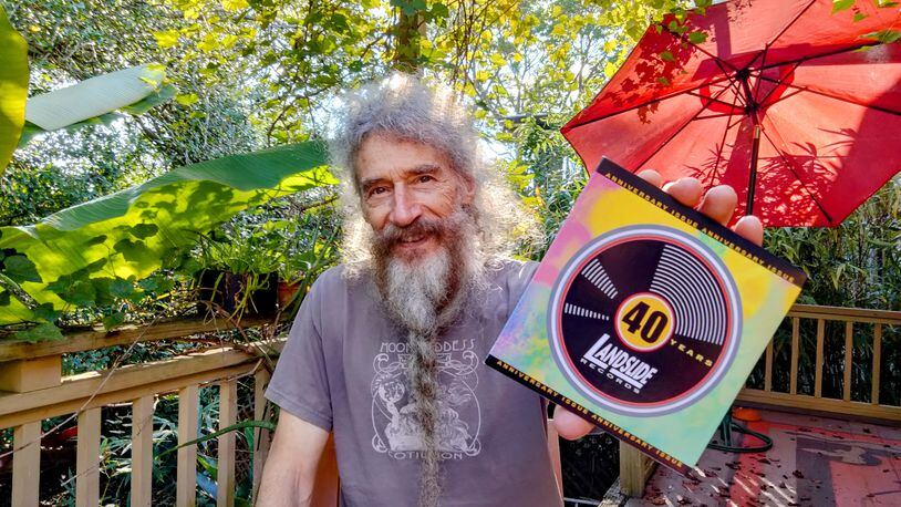 Artist Flournoy Holmes, on his back porch, holds the cover of the new Landslide Records compilation. (Photo by Brenda Stepp)
