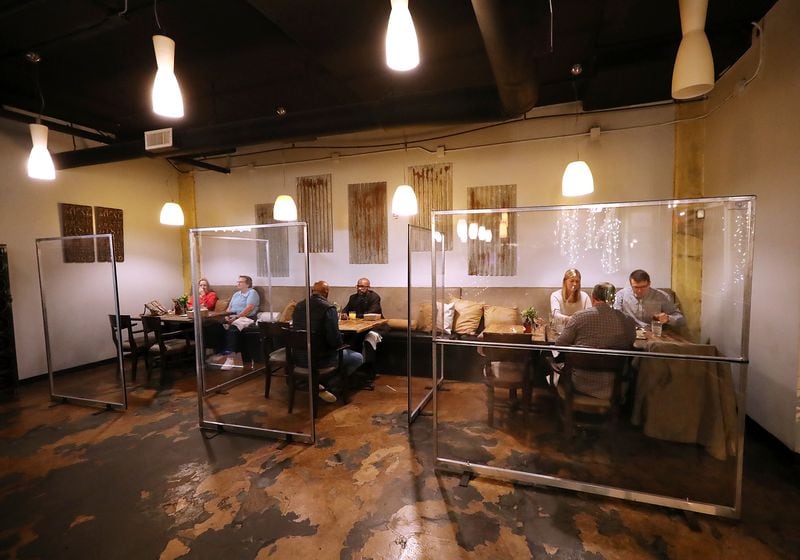 Diners fill plexiglass cubicles during the busy time of day, though busy is relative during a pandemic, at the peak dinner hour in Twisted Soul Cookhouse, on Wednesday, Dec. 9, 2020, in Atlanta.  “Curtis Compton / Curtis.Compton@ajc.com”