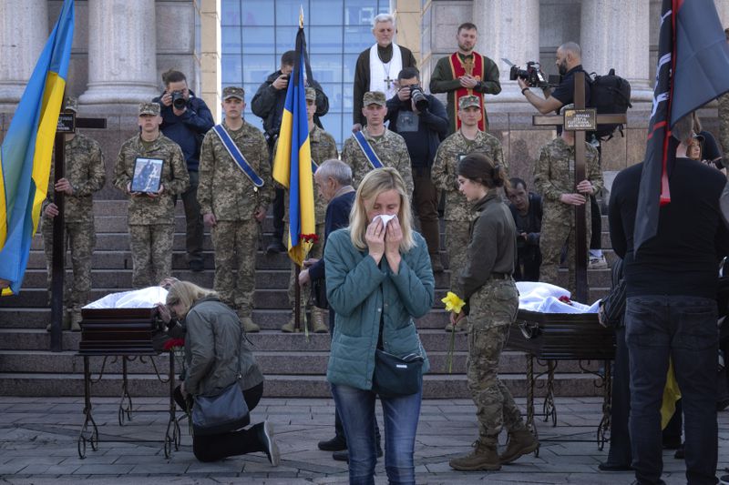 People pay respect at the coffins of Ukrainian servicemen Serhiy Konoval and Taras Petrushun, who were killed in a battle with the Russian troops, during the funeral ceremony in Independence square in Kyiv, Ukraine, Tuesday, April 9, 2024. (AP Photo/Efrem Lukatsky)