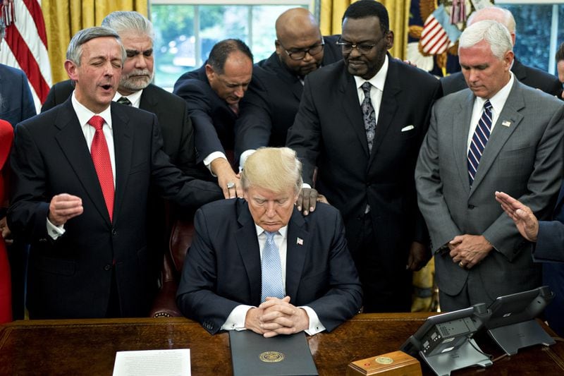 September 2017: President Donald Trump bows his head during a prayer while surrounded by U.S. Vice President Mike Pence (right), faith leaders and evangelical ministers after signing a proclamation declaring a day of prayer in the Oval Office of the White House.
