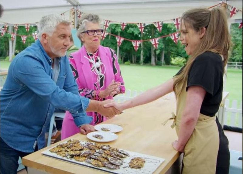 Baker Lottie Bedlow gets one of the coveted Paul Hollywood handshakes during the 2020 “Great British Baking Show,” which saw the contestants all living in a pandemic bubble. (Courtesy of Netflix)