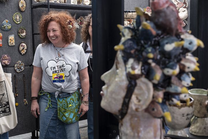 Betsy Khuri, of Woodstock, laughs while working her ceramics booth at the Dogwood Festival in Piedmont Park on Saturday, April 13, 2024.   (Ben Gray / Ben@BenGray.com)