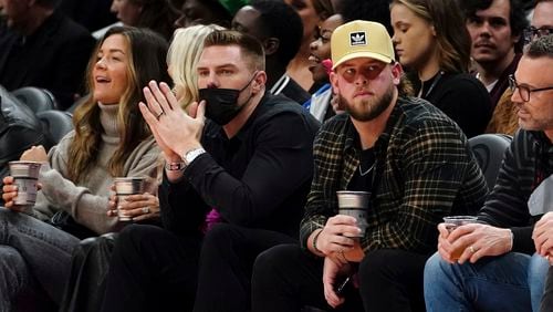 Atlanta Braves first baseman Freddie Freeman, center left, and relief pitcher A.J. Minter, center right, watch the first half of an NBA basketball game between the Atlanta Hawks and the Utah Jazz, Thursday, Nov. 4, 2021, in Atlanta. (AP Photo/John Bazemore)