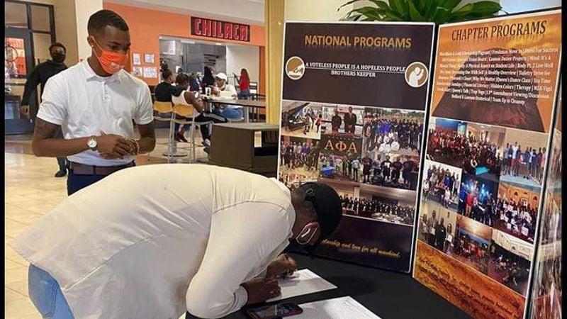 Savannah State University student government association president Khayree Hasan, left wearing a mask, mans a booth where he and other Alpha Phil Alpha Fraternity, Inc. members are involved in voter registration efforts. Hasan, 21, was unable to vote in the 2016 election, but is voting this year and eager to help other students vote. PHOTO CONTRIBUTED.