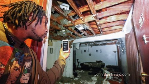 Jonathan Lackey uses a flashlight to look at damage after the roof collapsed on an apartment in Atlanta. JOHN SPINK / JSPINK@AJC.COM